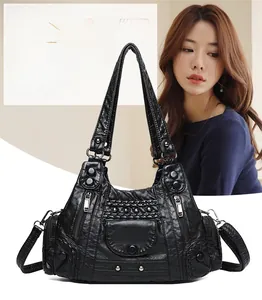 Detail of black pebbled leather tote bag with metallic studs and functional zip pockets
