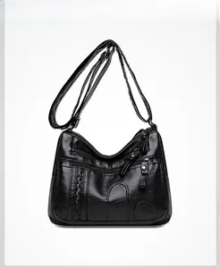 Detail of black PU leather crossbody bag featuring multiple zippers and woven texture