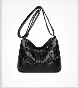 Close-up of black PU leather crossbody bag with triple zippers and woven texture details