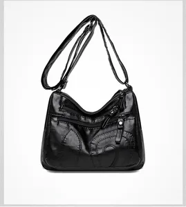 Detail of black PU leather crossbody bag featuring lychee texture and metallic zippers