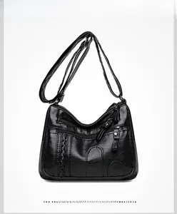 Detail of black soft PU leather crossbody bag featuring triple front zippers and woven stripes