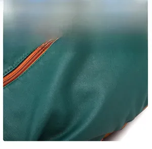 Macro detail of cross-grain green faux leather texture and smooth brown zipper on backpack