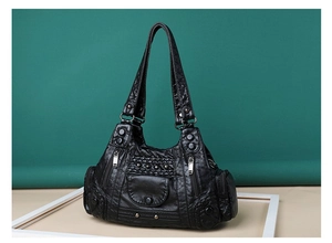 Detail of vintage black PU leather handbag with rivet accents and zipper pocket