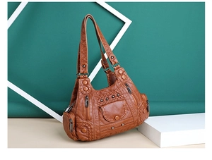 Detailed view of brown washed PU leather handbag with vintage rivets and zipper pockets