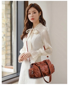 Detail of vintage brown PU leather crossbody bag featuring braided trim and stud accents