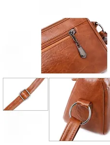 Close-up of gun-black metal hardware and litchi texture on brown PU leather bag