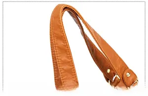 Detail of soft brown PU leather shoulder strap with golden metal rivets and texture