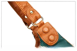 Detail of green pebble leather bag with brown strap and golden metal hardware connector