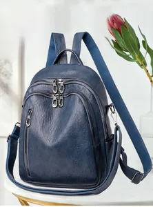 Detail of blue pebbled leather backpack with dual zippers and side pockets on a white surface