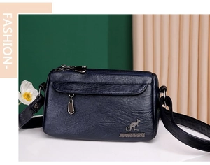 Detail of navy blue pebble leather crossbody bag featuring embossed kangaroo logo and metal zipper