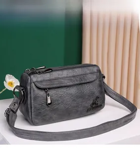 Detailed close-up of grey soft PU leather crossbody bag with kangaroo logo and twin zippers