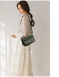 Detail of dark green PU leather crossbody bag featuring an adjustable strap and logo