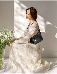 Detail of soft black PU leather crossbody bag with pleated texture and kangaroo logo