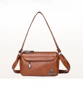 Detailed view of brown lychee texture leather bag with metal kangaroo logo and dual zippers