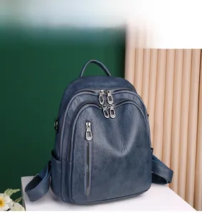 Detail view of large capacity dark blue leather backpack with multiple zipper compartments