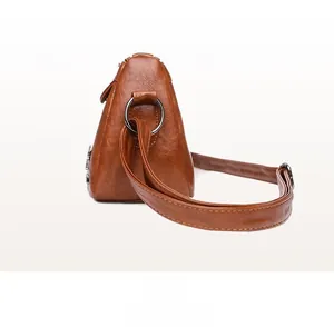 Detail shot of caramel brown faux leather bag showing soft lychee texture and silver rings