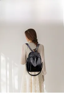 Detail of black leather backpack featuring silver zippers and multiple functional pockets