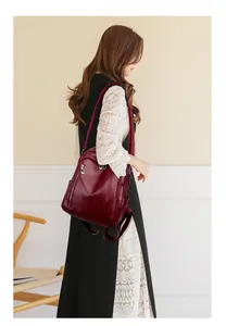 Deep red multi-pocket leather backpack shown on model in a stylish indoor lifestyle setting