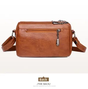 Detailed back view of brown PU leather crossbody bag featuring a metal zipper pocket