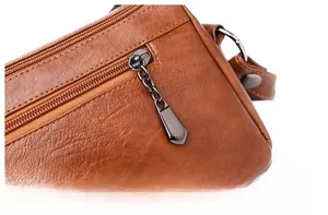 Detailed close-up of dark grey metal zipper and brown textured leather on handbag