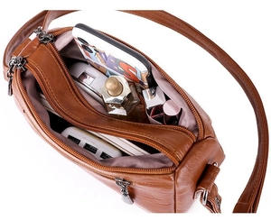 Detail showing the large interior capacity and multi-compartment design of the brown cross-body bag