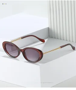 Detail of oval sunglasses featuring purple gradient lenses and gold metal chain temples