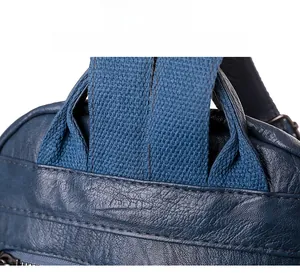 Close-up of precise stitching on blue soft leather backpack with fabric strap joint