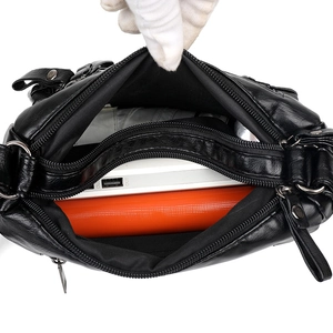 Spacious interior of a black soft leather crossbody bag with items for storage display