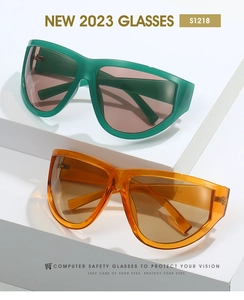 Close-up of green and orange Y2K cyberpunk oversized eyewear on white geometric stands