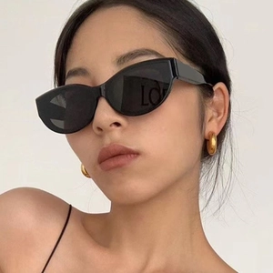 Gros plan de lunettes de soleil œil-de-chat noires et créoles dorées portées par un mannequin