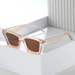 Minimalist square sunglasses with champagne frames and brown lenses on a white platform