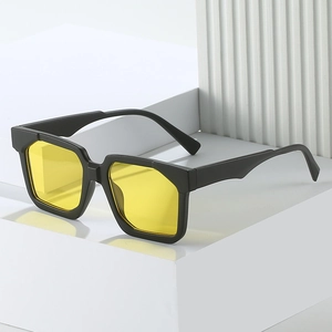 Eckige schwarze Sonnenbrille mit gelben Gläsern auf einem weißen Sockel präsentiert