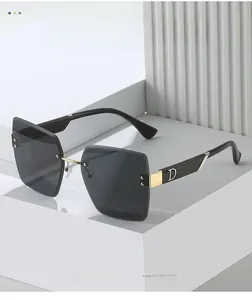 Close-up of rimless square sunglasses with gold metal D-shaped temple accents and dark lenses