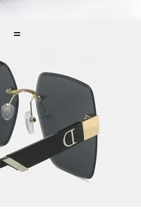 Close-up of square rimless sunglasses showing gold metal bridge and D logo on temple