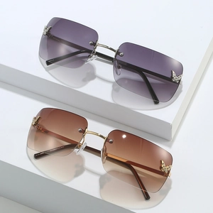 Frameless Y2K sunglasses with butterfly crystals and gradient lenses on a white display