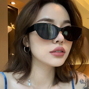 Lunettes de soleil œil de chat rétro portées par un mannequin en décor chaud