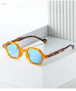 Detail of orange hexagon sunglasses with blue lenses on white geometric stand