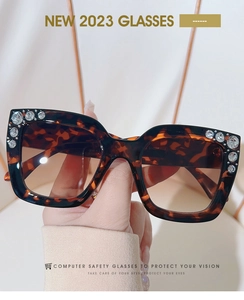 Close-up of tortoise shell square sunglasses with sparkling rhinestone accents on frame