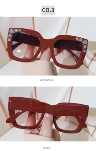 Detail view of red oversized square sunglasses featuring sparkling rhinestone embellishments
