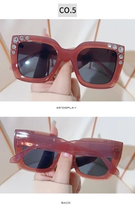 Detail of square amber sunglasses with rhinestone accents and dark shaded lenses