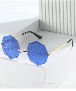 Close-up of blue octagonal rimless sunglasses with spider web lens and gold metal frame