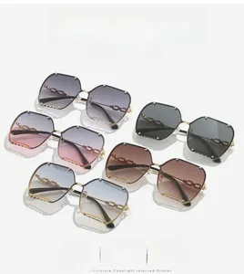 Close-up of rimless gradient sunglasses featuring gold chain-link arms and rivet accents