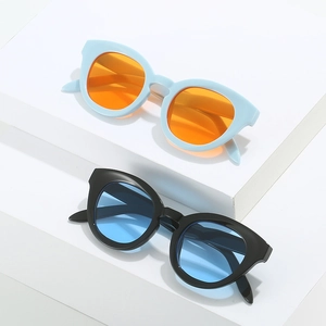 Retro oval cat-eye sunglasses with blue and black frames on white geometric stand