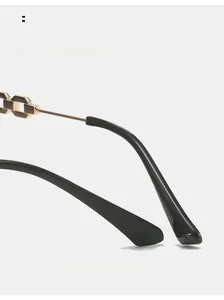 Detail of curved rimless sunglasses temple with gold metal chain and black ear sleeve