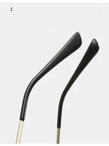 Close-up of curved black resin tips and slim gold metal temples of oversized sunglasses