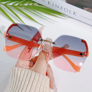 Frameless oversized sunglasses with grey-pink gradient lenses and orange metal temples
