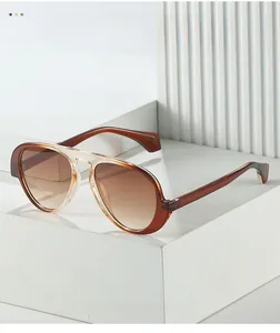 Dettaglio di occhiali da sole aviator con montatura sfumata su supporti geometrici bianchi