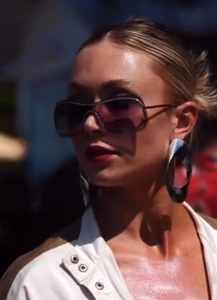 Detail of dark gradient Y2K sunglasses and silver oversized round metal earrings on a model