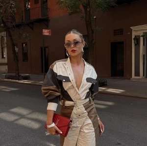 Detail of color-block jumpsuit with metal buttons, belt and red luxury envelope bag