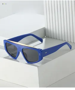 Detail of dark blue oversized sunglasses with gold metal bar on white geometric blocks